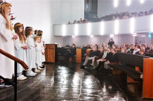 Joukko enkeliksi pukeutuneita lapsia seisoo Oriveden kirkon kuorin portailla kynttilät käsissään.