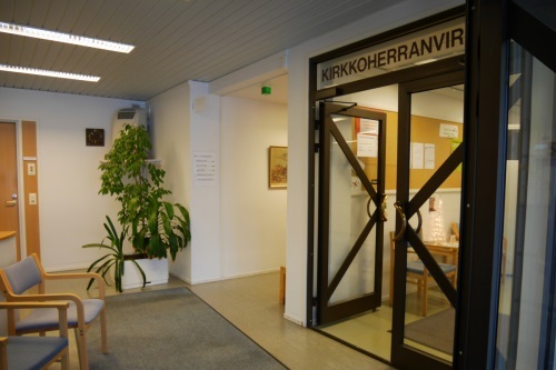 Kuva seurakuntakeskuksen kirkkoherranviraston aulasta kohti viraston ovia.